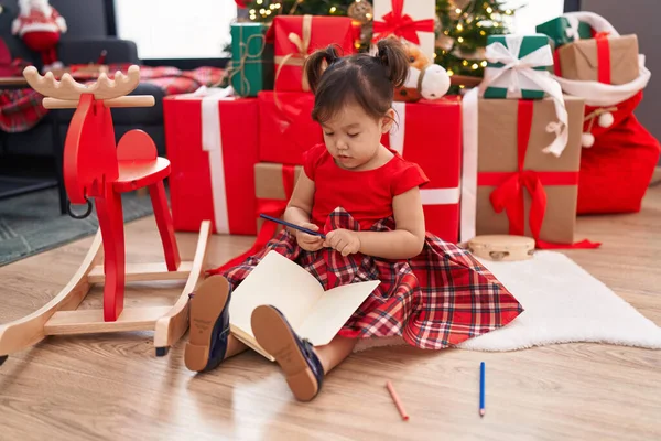 Adorable Chinese Girl Drawing Notebook Sitting Floor Christmas Tree Home — ストック写真