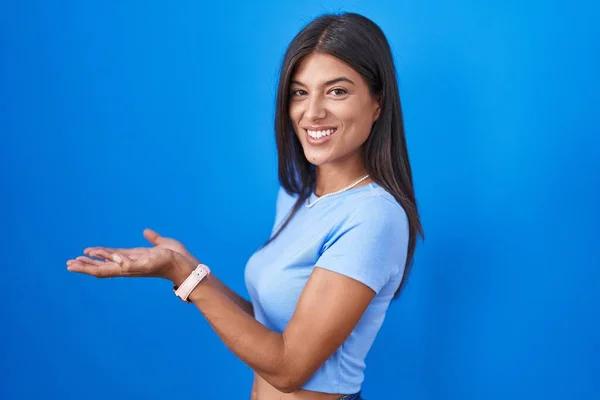 Brunette Young Woman Standing Blue Background Pointing Aside Hands Open — Stock fotografie