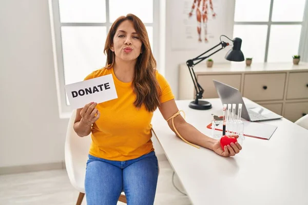 Hispanic woman supporting blood donation looking at the camera blowing a kiss being lovely and sexy. love expression.