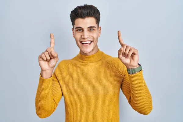 Junger Hispanischer Mann Steht Vor Blauem Hintergrund Und Lächelt Erstaunt — Stockfoto
