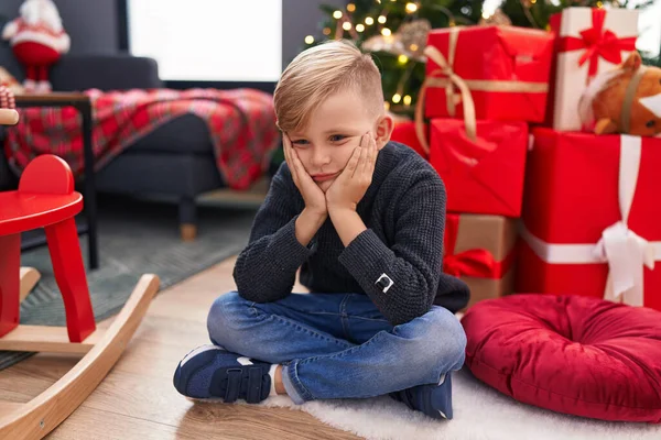 Sevimli Çocuk Evde Şüpheli Bir Ifadeyle Noel Ağacının Yanında Oturuyor — Stok fotoğraf