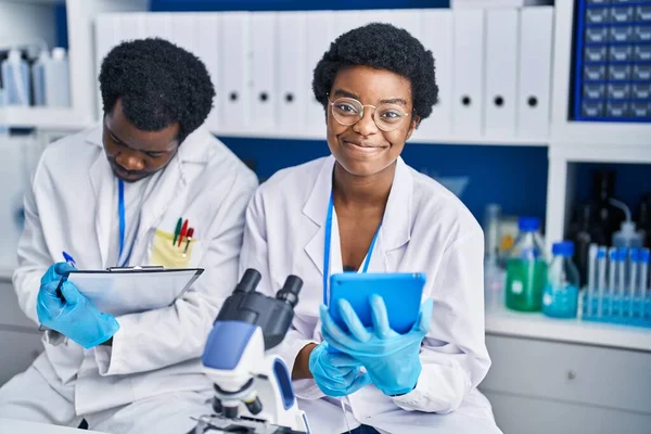 アフリカ系アメリカ人の男性と女性の科学者は 研究室で文書にタッチパッドを使用して — ストック写真
