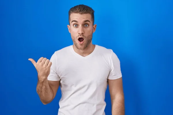 Young Caucasian Man Standing Blue Background Surprised Pointing Hand Finger — Stock Photo, Image