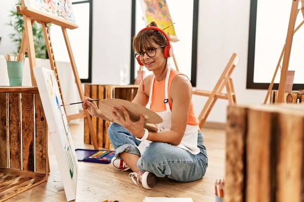 stock image Young hispanic woman listening to music drawing at art studio