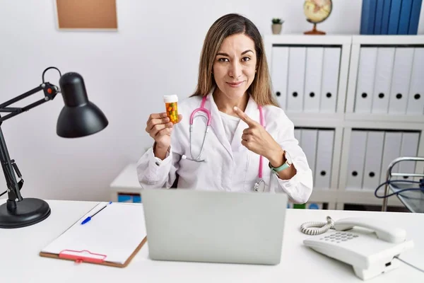 Young Hispanic Woman Wearing Doctor Uniform Holding Pills Clinic Pointing — Photo