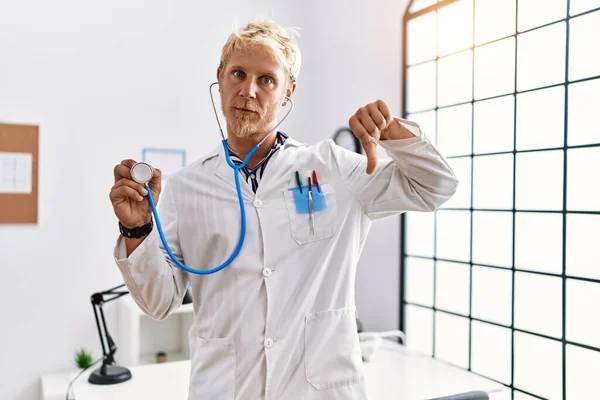 Young Blond Man Wearing Doctor Uniform Holding Stethoscope Clinic Angry — ストック写真