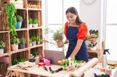 Çiçekçide dizüstü bilgisayar kullanan güzel İspanyol bir çiçekçi kadın.