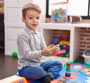 Anaokulunda yerde oturmuş matematik oyunu oynayan sevimli çocuk.