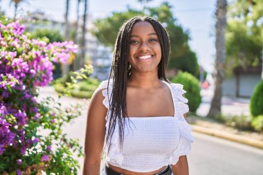 Genç Afrikalı Amerikalı kız gülümseyerek şehirde mutlu mesut duruyor..