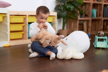 Sevimli çocuk evde yerde oturan bebeklerle oynuyor.