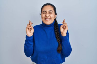 İzole edilmiş arka planda dikilen genç İspanyol kadın umut ve gözleriyle gülümseyerek bana işaret ediyor. Şans ve batıl inançlar. 