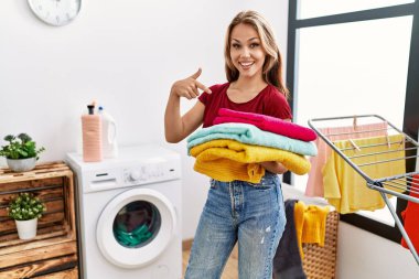 Elinde temiz çamaşırları olan beyaz bir kadın mutlu bir şekilde elini ve parmağını gösterdi. 