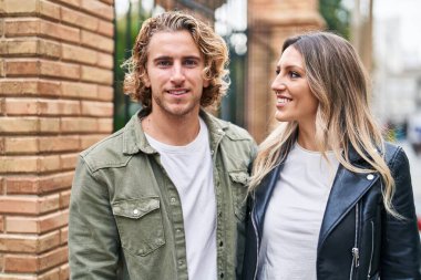 Kadın ve erkek gülümsüyor. Kendilerine güveniyorlar. Sokakta sarılıyorlar.