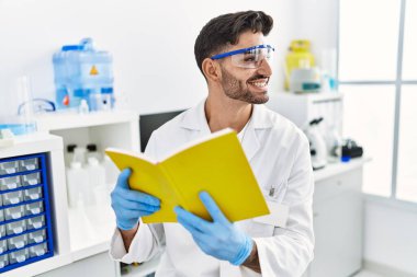 Laboratuvarda bilimsel olarak kitap okuyan yakışıklı İspanyol adam.