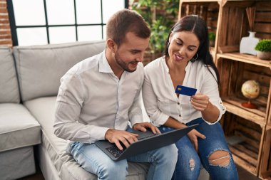 Man and woman couple using laptop and credit card at home