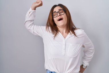 Esmer kadın, beyaz izole edilmiş arka planda duruyor. Yorgun ve rahat, uykulu ve sabahın erken saatlerinde esniyor. 