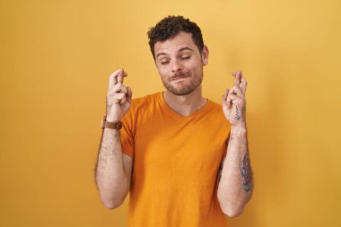 Sarı arka planda dikilen Latin kökenli genç adam umut ve gözlerin kapalı bir şekilde gülümseyerek bana işaret etti. Şans ve batıl inançlar. 