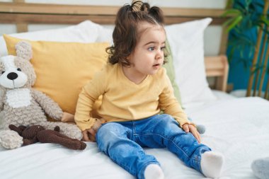 Sevimli İspanyol kız yatak odasında rahat bir ifadeyle yatakta oturuyor.