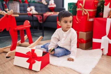 Tapılası İspanyol bebek evde Noel ağacının yanında yerde oyuncakla oynuyor.