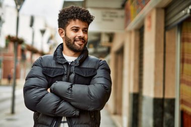 Kasabada çapraz kollarla gülümseyen genç bir Arap.