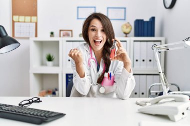 Klinikte elinde elektronik sigara tutan genç doktor gururla bağırıyor, zaferi kutluyor ve kollarını kaldırarak başarıyı kutluyor. 