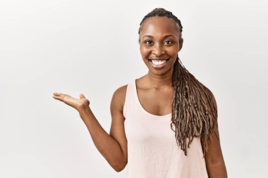 Örgü örgülü siyah bir kadın izole edilmiş arka planda gülümsüyor ve avucunun içi gibi kameraya bakıyor.. 