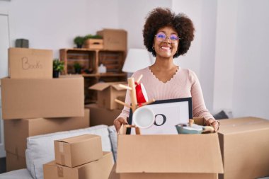Young african american woman moving to a new home smiling with a happy and cool smile on face. showing teeth. 