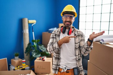 Evde çalışan sakallı genç İspanyol adam kameraya hayret ediyor ve gülümsüyor.. 