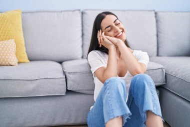 Genç İspanyol kadın evde oturmuş kendinden emin gülümsüyor.