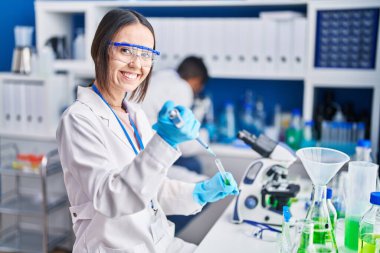 Man and woman scientists pouring liquid on test tube at laboratory