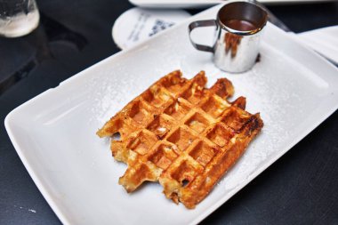  Tahta yüzeyde bir tabak waffle ve çikolata sosu.