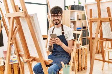 Sanat stüdyosunda akıllı telefon çizimi yapan genç bir İspanyol sanatçı..