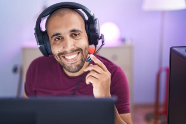 Oyun odasındaki masada kendinden emin gülümseyen genç Latin adam.