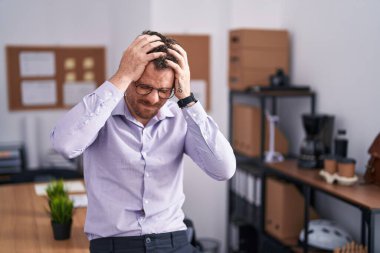 Ofisteki genç İspanyol adam acı ve migren yüzünden çaresiz ve stresli baş ağrısından muzdarip. Eller başının üstünde.. 