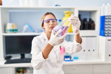 Laboratuvarda sıvıyı ölçen genç İspanyol bilim kadını.