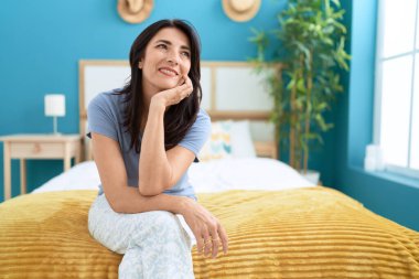 Orta yaşlı İspanyol kadın yatakta kendinden emin bir şekilde oturuyor.