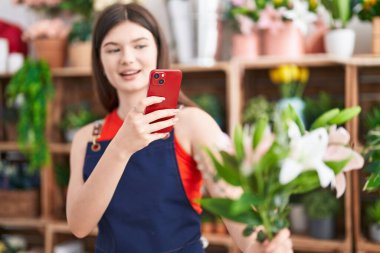 Young caucasian woman florist make photo by smartphone to flowers at florist