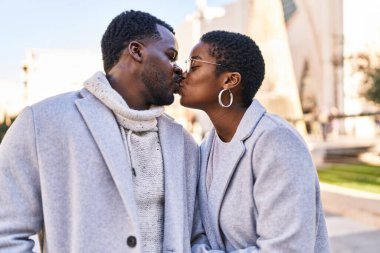 Man and woman couple standing together kissing at street