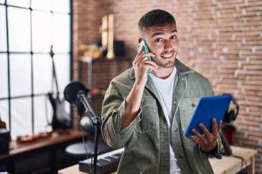 Genç İspanyol müzisyen, müzik stüdyosundaki touchpad 'i kullanarak akıllı telefondan konuşuyor.