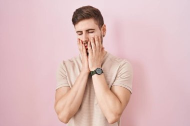 Pembe arka planda duran İspanyol sakallı adam. Yüzü, depresyonu ve üzüntüyü örten yorgun eller, sorun yüzünden üzgün ve tedirgin. 