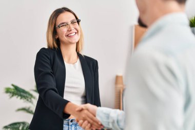 Genç adam ve kadın iş adamları ofiste el sıkışıyor.