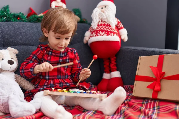 愛らしいHispanic女の子遊びますXylophone座っています上のソファによってクリスマス装飾で家 — ストック写真