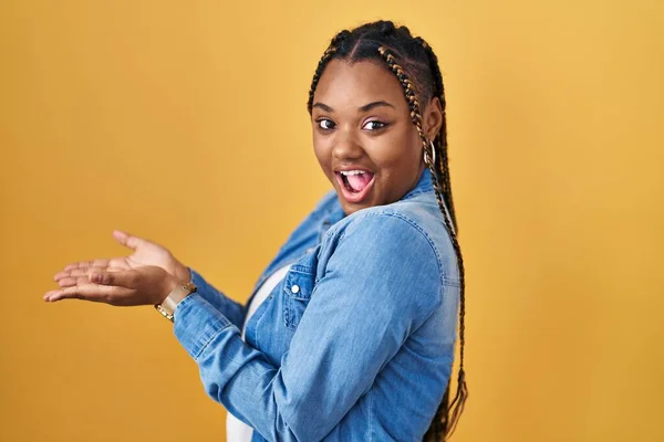 African American Woman Braids Standing Yellow Background Pointing Aside Hands — Stockfoto