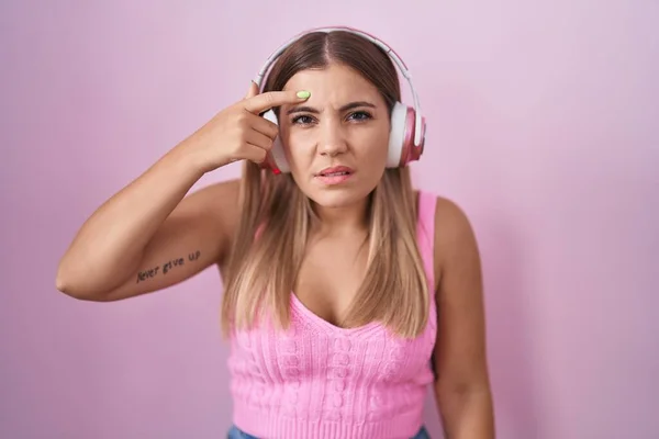 Young Blonde Woman Listening Music Using Headphones Pointing Unhappy Pimple — Foto de Stock