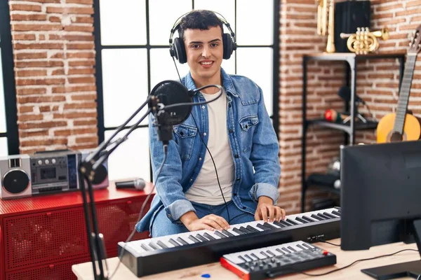 Young non binary man musician singing song playing piano keyboard at music studio