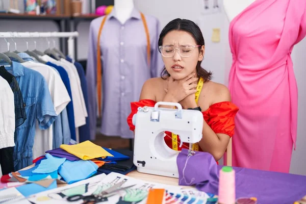 Hispanic Young Woman Dressmaker Designer Using Sewing Machine Shouting Suffocate — Stockfoto