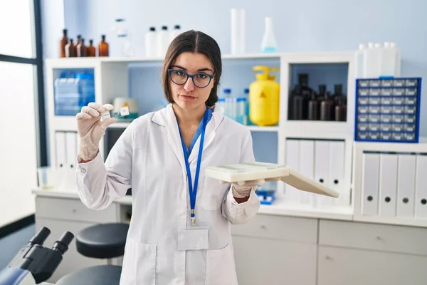 Young hispanic woman working at scientist laboratory with blood samples depressed and worry for distress, crying angry and afraid. sad expression.