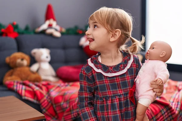Beyaz Kız Elinde Oyuncak Bebekle Evde Noel Süslemelerinin Yanında Duruyor — Stok fotoğraf