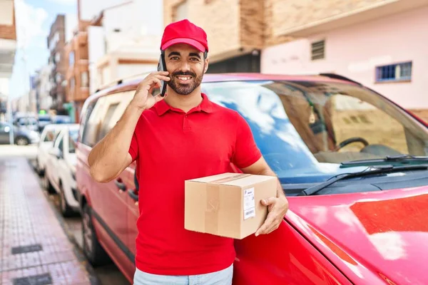 Genç İspanyol kurye caddedeki akıllı telefon paketinden konuşuyor.