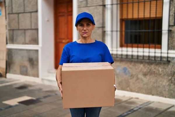 Middle age brunette woman working delivering big package depressed and worry for distress, crying angry and afraid. sad expression.